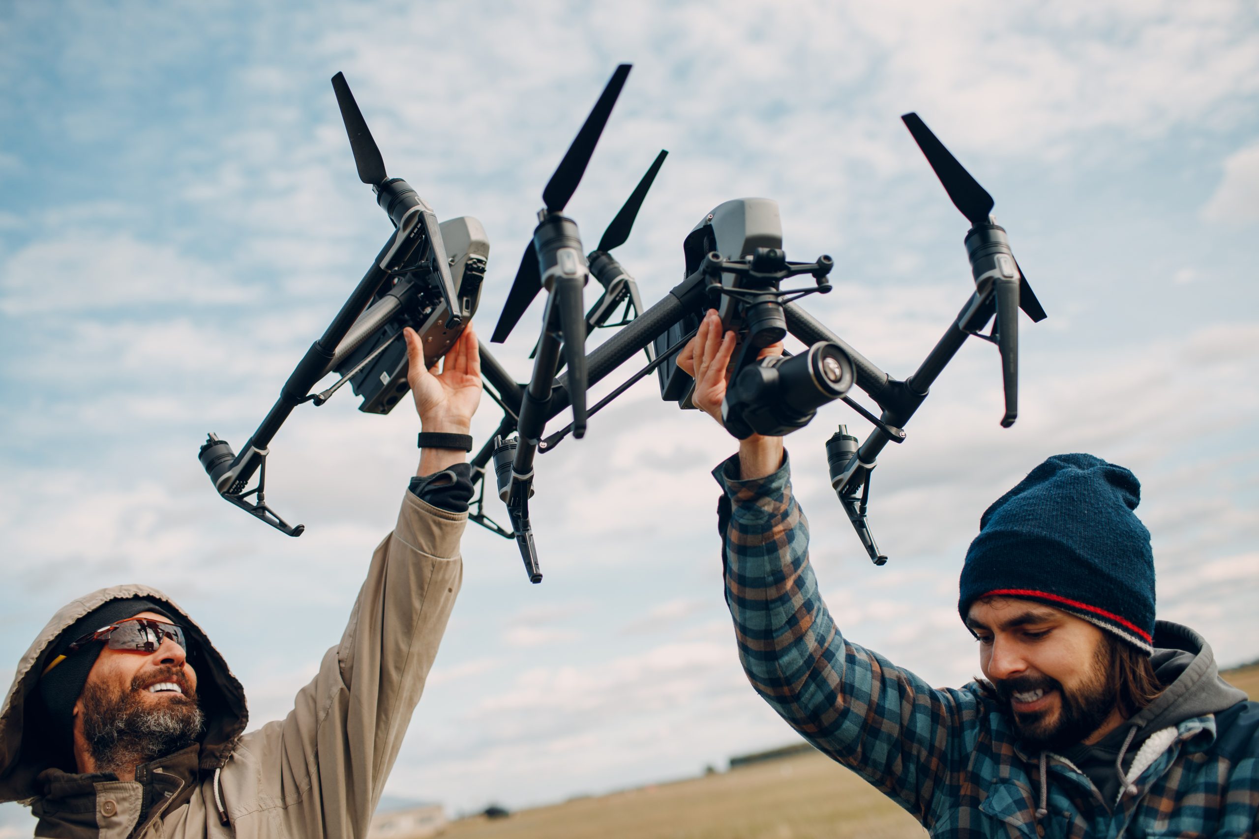 Two Men Pilots Holding Quadcopter Drone Hands Outside Field Scaled